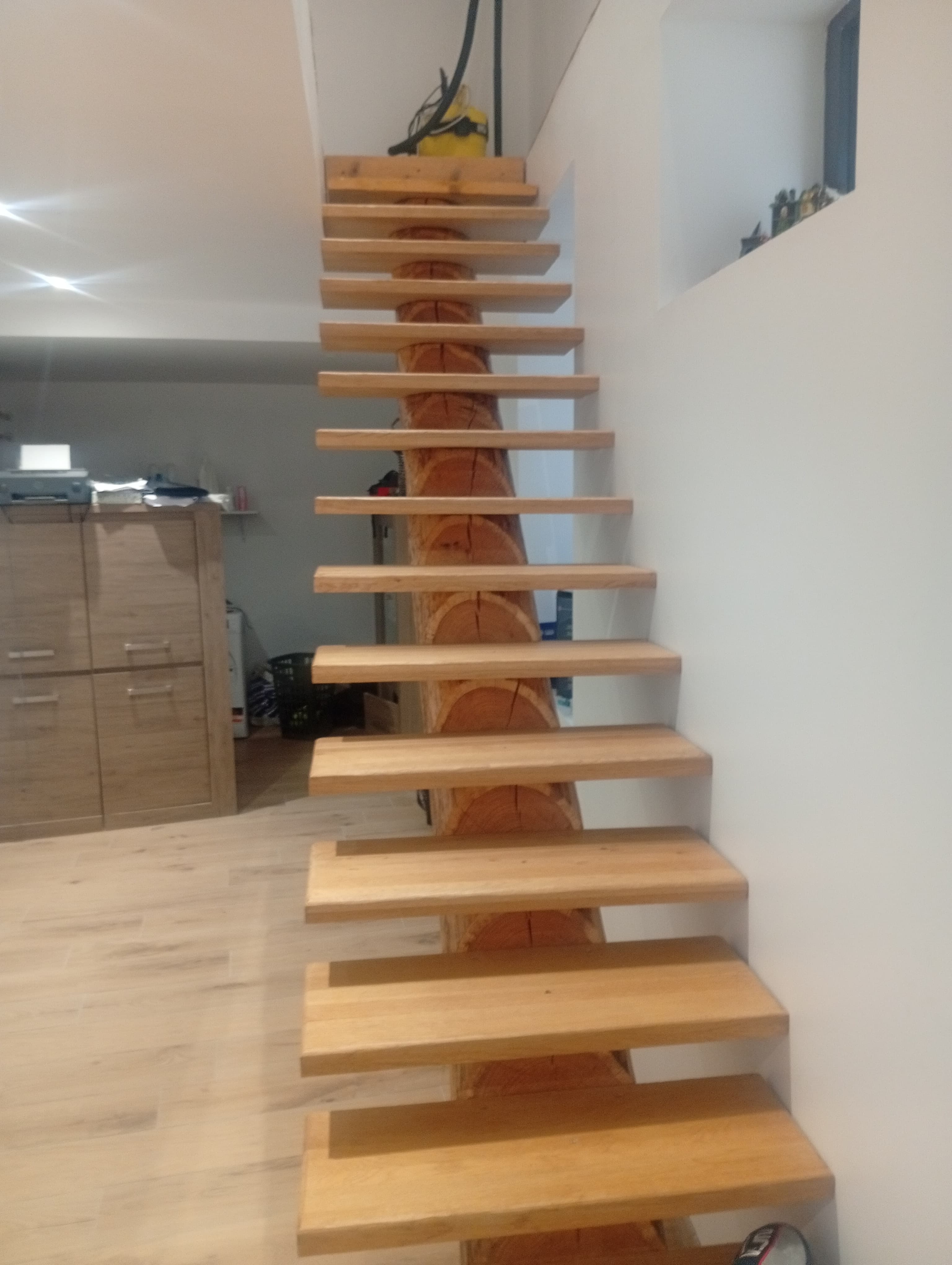 Escalier à limon central en bois massif avec marches en chêne en porte-à-faux, réalisé sans contremarches pour un rendu aérien et contemporain. Une pièce maîtresse de menuiserie structurelle qui allie robustesse naturelle et élégance architecturale, valorisant immédiatement tout espace intérieur.